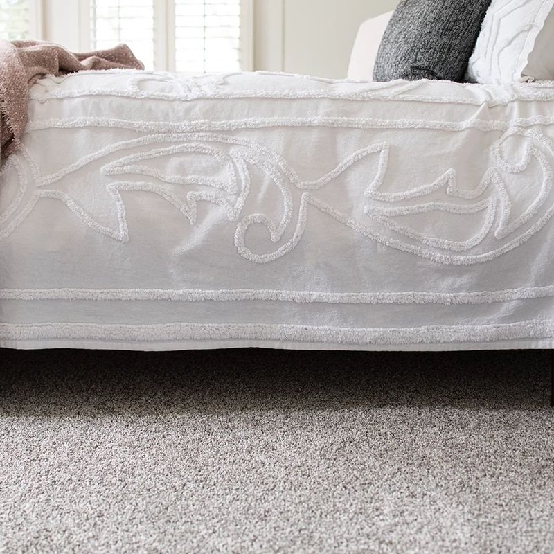 closeup of bed on carpet with small side table - Shamrock Carpets in Uniontown, PA