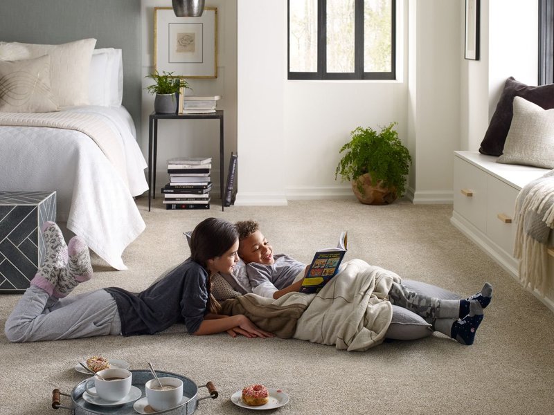 two kids laying on floor reading a book - shamrock carpets in pa